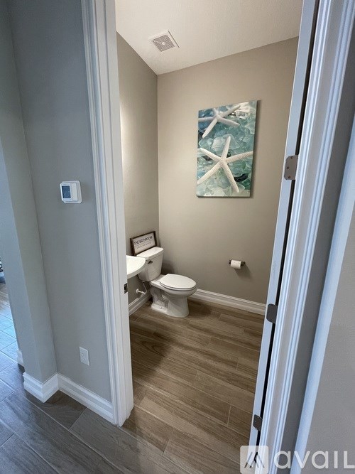 A bathroom with a toilet and a painting of a starfish on the wall.