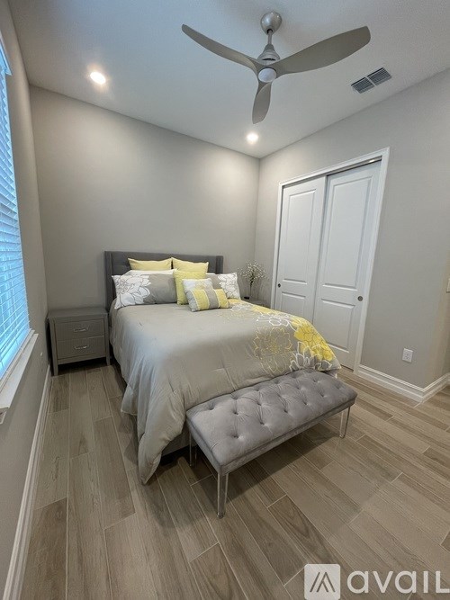 A bedroom with a bed, a bench, and a ceiling fan.