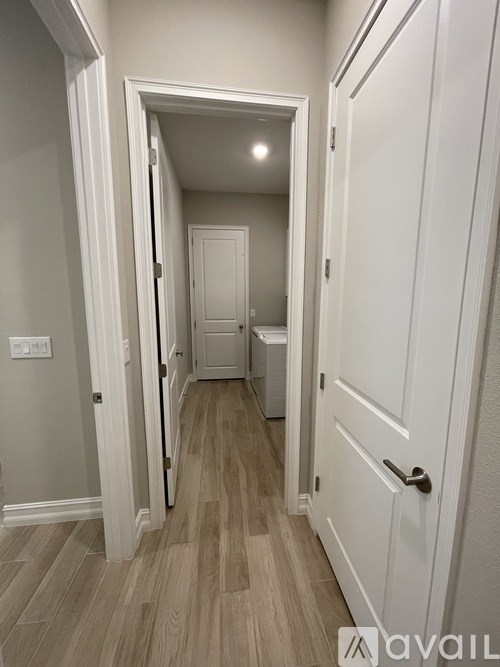 A hallway with a white door and a wooden floor.