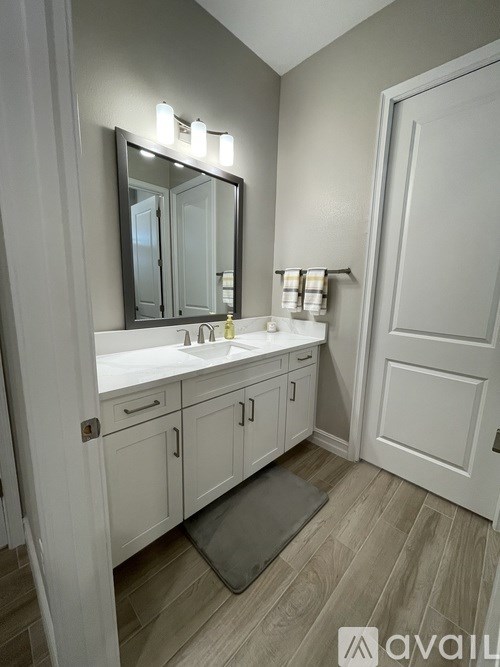 A bathroom with a sink, mirror, and cabinets.