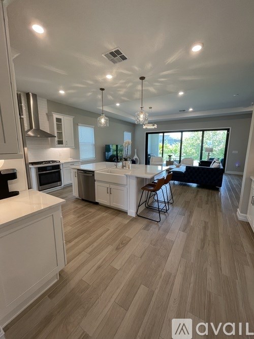 A modern kitchen with wooden flooring and a dining area with a table and chairs.