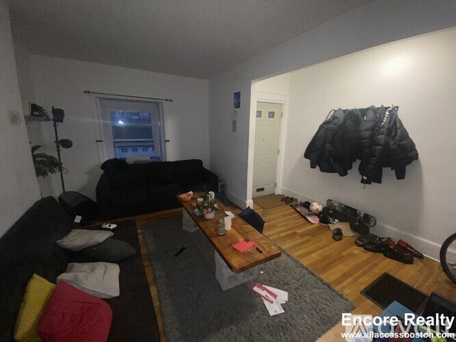 A room with a black couch, a wooden table, and a bicycle in the corner.