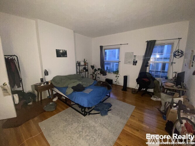 A bedroom with a bed, a desk, and a chair.