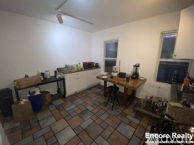A kitchen with a tile floor and a table with chairs.