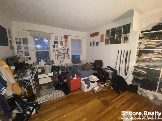 A room with a lot of clutter and a wooden floor.