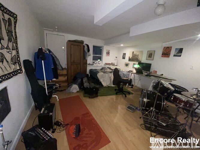 A room with a drum set and a red rug.