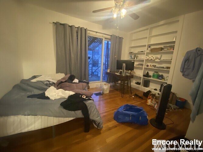 A bedroom with a bed, desk, and a window with curtains.