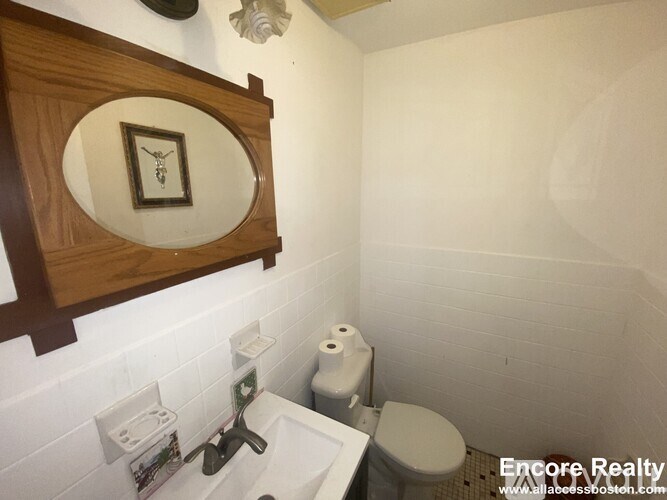 A bathroom with a toilet, sink, and mirror.