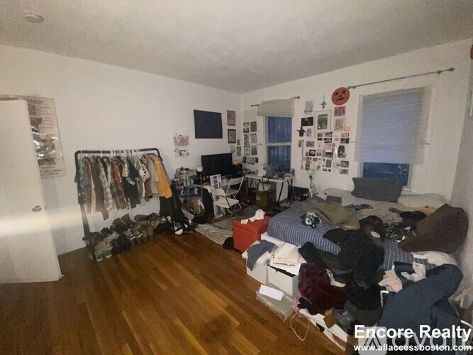 A room with a lot of clothes and a whiteboard on the wall.