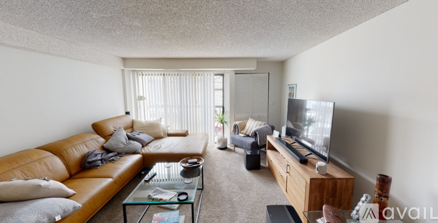 A living room with a tan couch, a glass coffee table, and a flat screen TV.