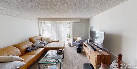 A living room with a tan couch, a glass coffee table, and a flat screen TV.