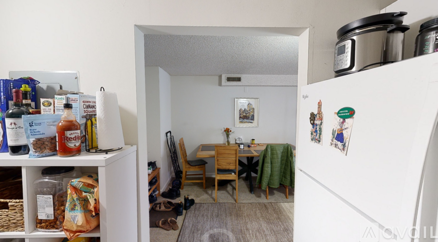 A kitchen with a refrigerator, a table and chairs, and a dining area.