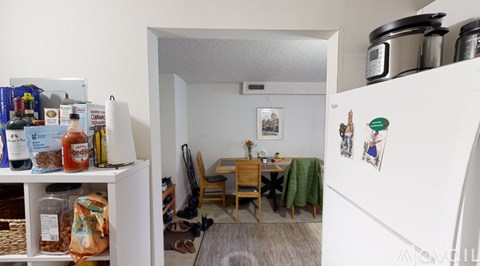 A kitchen with a refrigerator, a table and chairs, and a dining area.