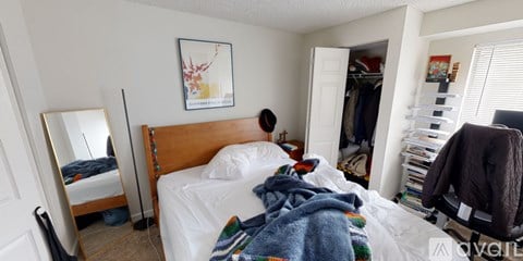 A bedroom with a bed, a chair, and a closet.