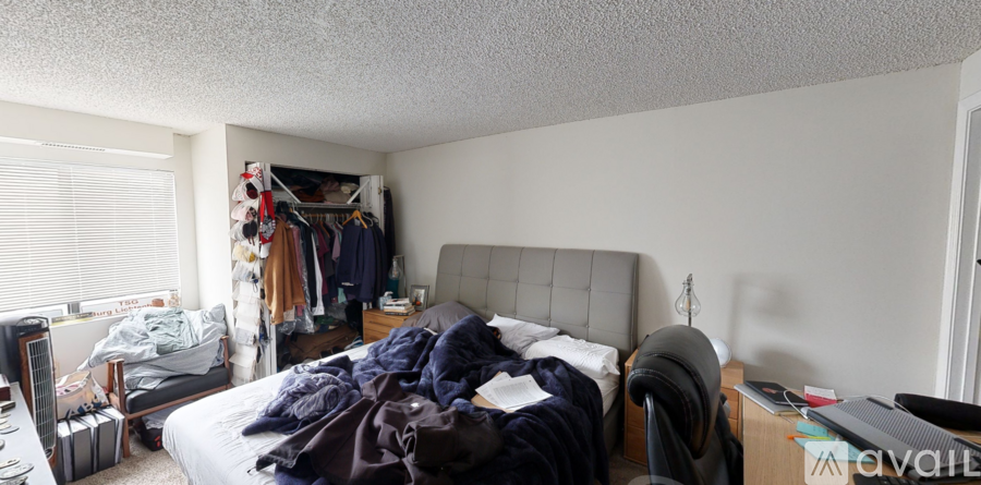 A messy bedroom with a bed, dresser, and closet.