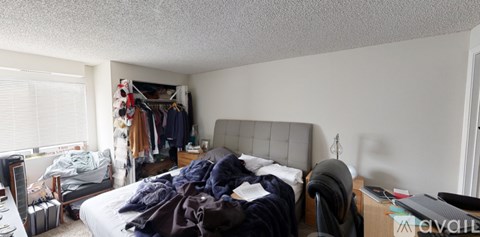 A messy bedroom with a bed, dresser, and closet.