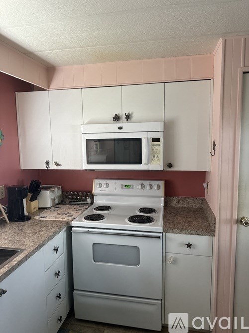 A kitchen with a white stove and microwave above it.