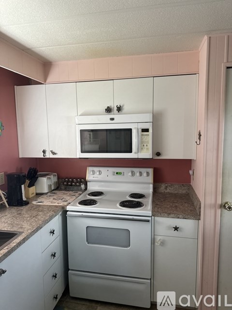 A kitchen with a white stove and microwave above it.
