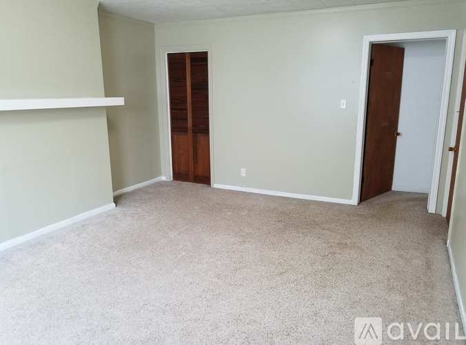 A room with a carpeted floor and two doors.