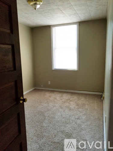 A room with a carpeted floor, a door, and a window.
