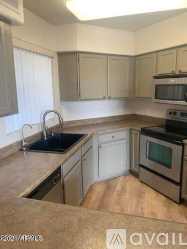 A kitchen with a sink, stove, and cabinets.