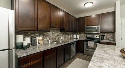 A kitchen with dark wood cabinets and a granite countertop.