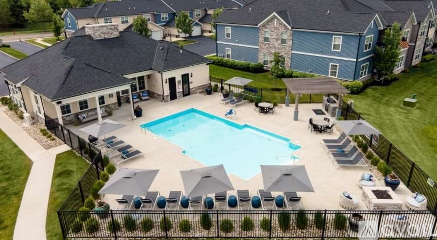 A large swimming pool surrounded by a black fence and lounge chairs.
