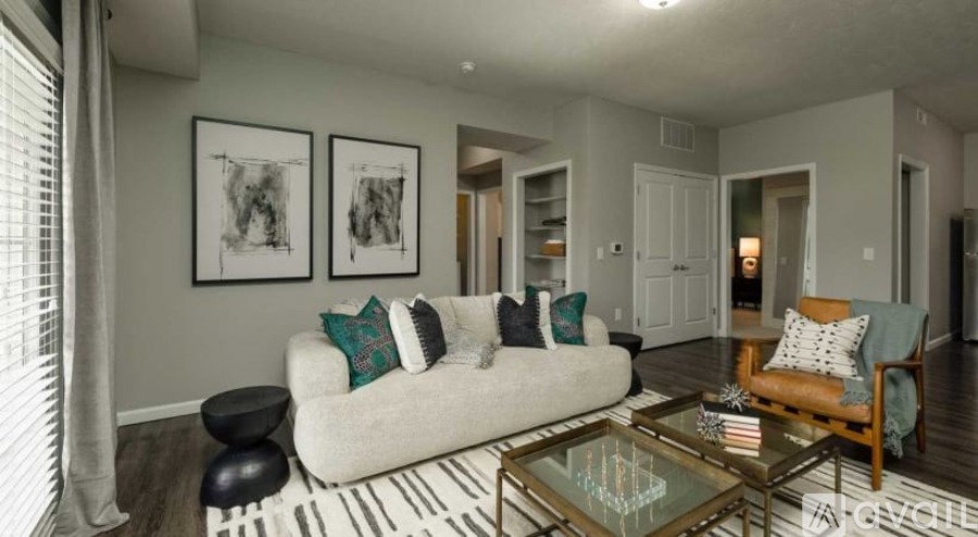 A living room with a white couch, a glass coffee table, and a striped rug.