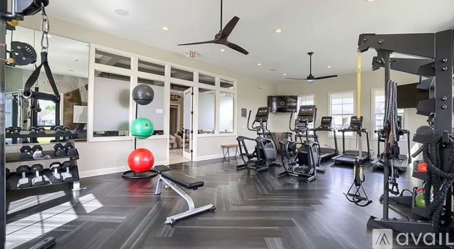 A gym with a variety of equipment including a bench, weights, and a fan.