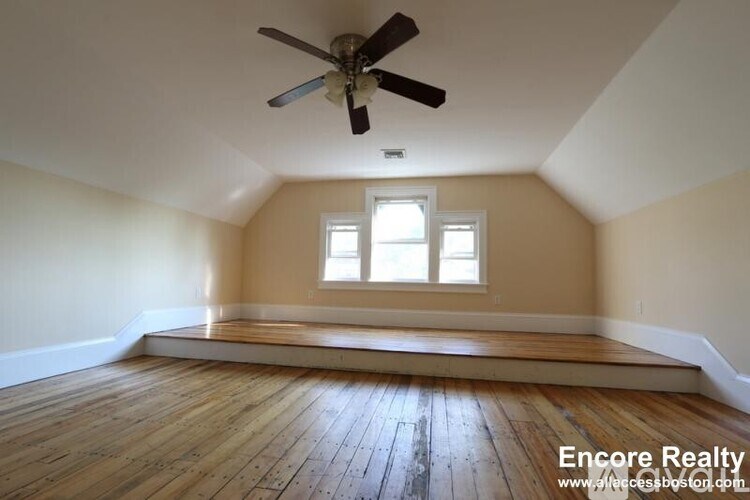 A room with a ceiling fan and wooden floors.