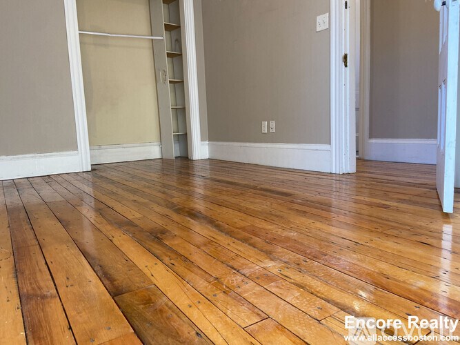 A room with wooden flooring and white walls.