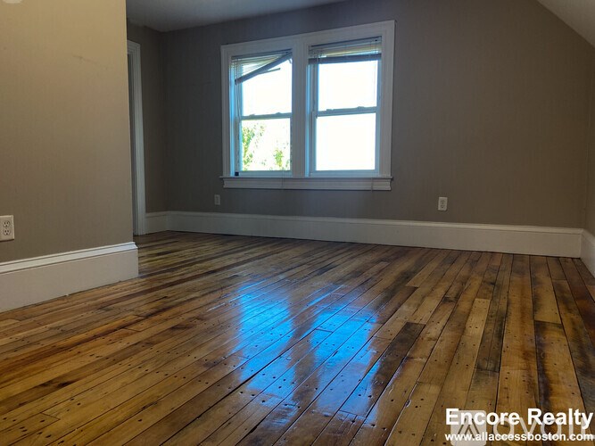 A room with wooden flooring and a window.