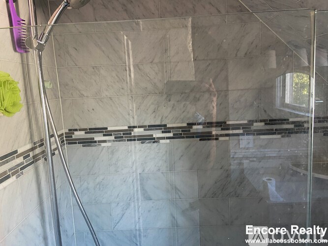 A bathroom with a shower area and a glass door.