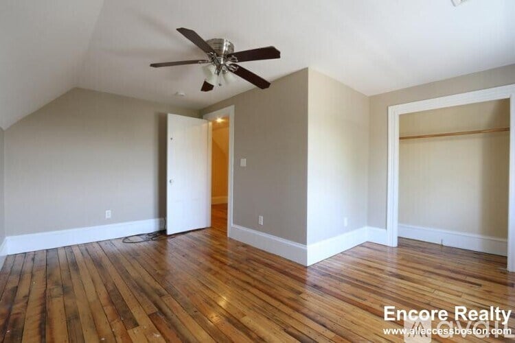 A room with a ceiling fan and wooden floors.