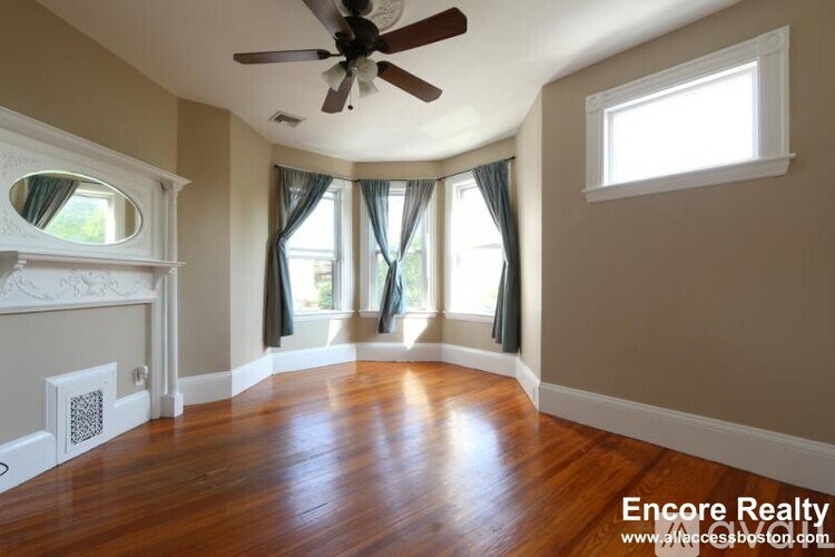 A room with a ceiling fan and a fireplace.