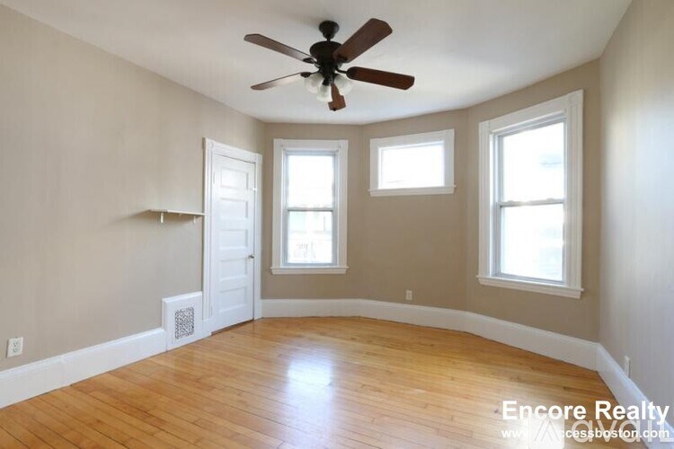 A room with a ceiling fan and three windows.