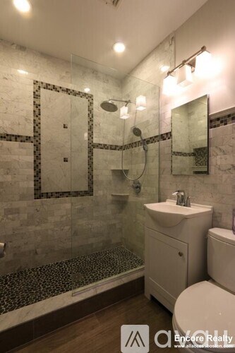 A bathroom with a marble tile shower and a white toilet.
