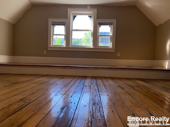 A room with wooden floors and two windows.