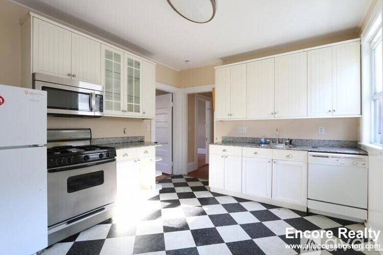A kitchen with white appliances and black and white checkered floor.