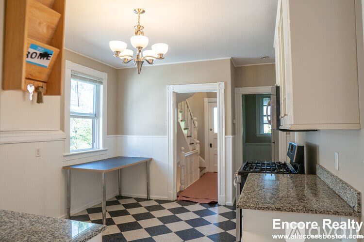 A kitchen with a checkered floor and a chandelier.