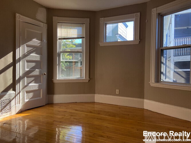 A room with a wooden floor and a staircase leading to the upper floor.