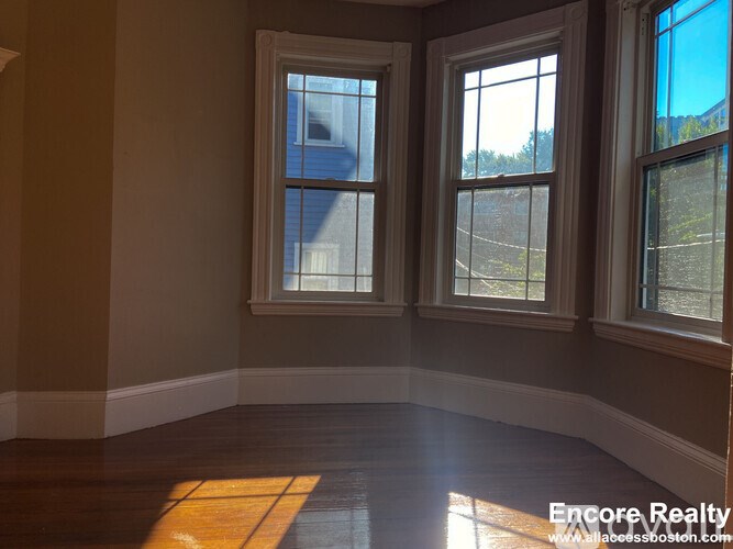 A room with two windows and a wooden floor.