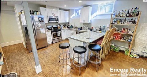 A kitchen with white cabinets and a wooden floor.