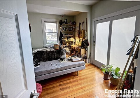 A dog is lying on a bed in a room with a wooden floor.