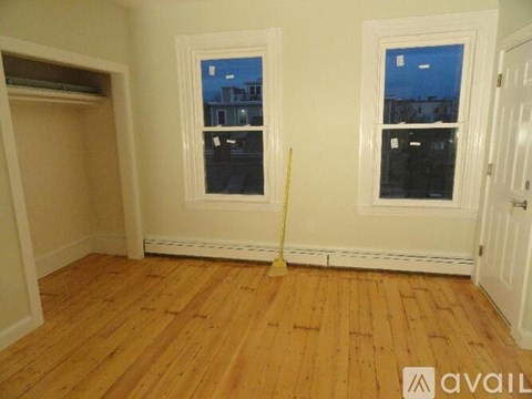 A room with wooden floors and two windows.