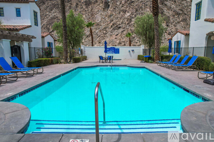 A pool surrounded by chairs and a mountain in the background.
