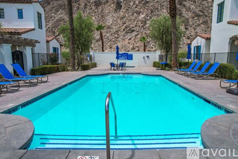 A pool surrounded by chairs and a mountain in the background.