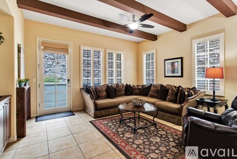 A living room with a brown couch and a rug.