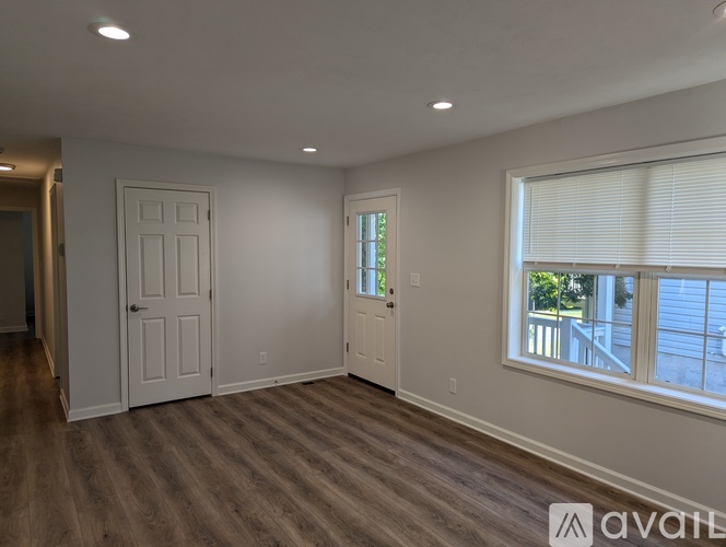 A spacious room with a door, window, and wooden flooring.