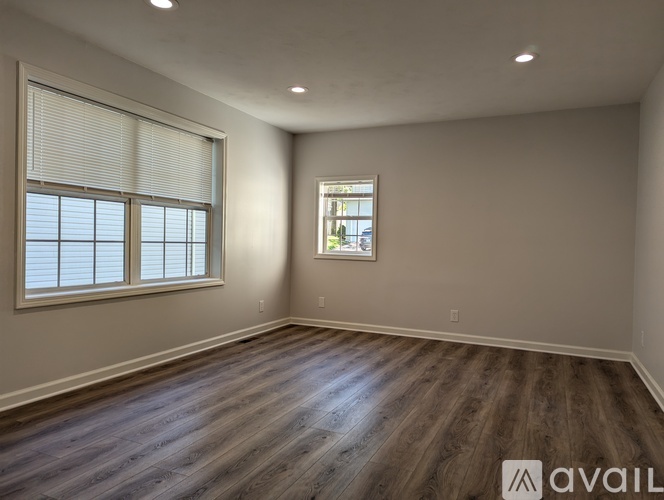 A room with wooden flooring and a window with blinds.